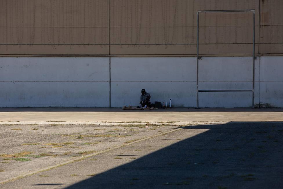 Un hombre descansa a la sombra junto al albergue de temporeros en Fira de Lleida