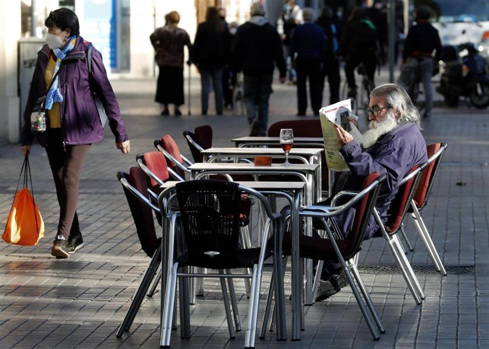Un hombre lee un periódico en la terraza de un bar de Barcelona que han reabierto este lunes