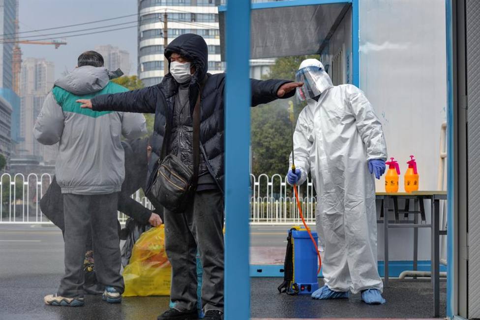 Un trabajador del hospital de Wuhan desinfecta a un visitante