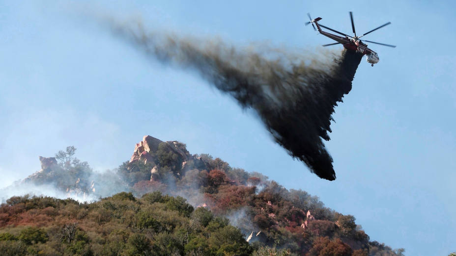 Un helicóptero descarga agua sobre uno de los incendios de California
