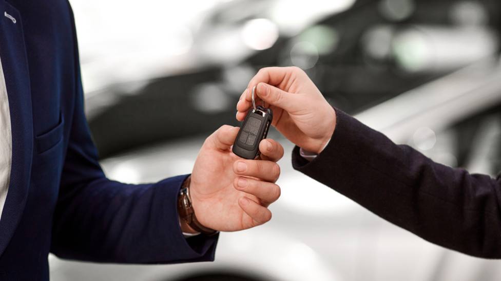 Una persona entrega las llaves del coche a otra