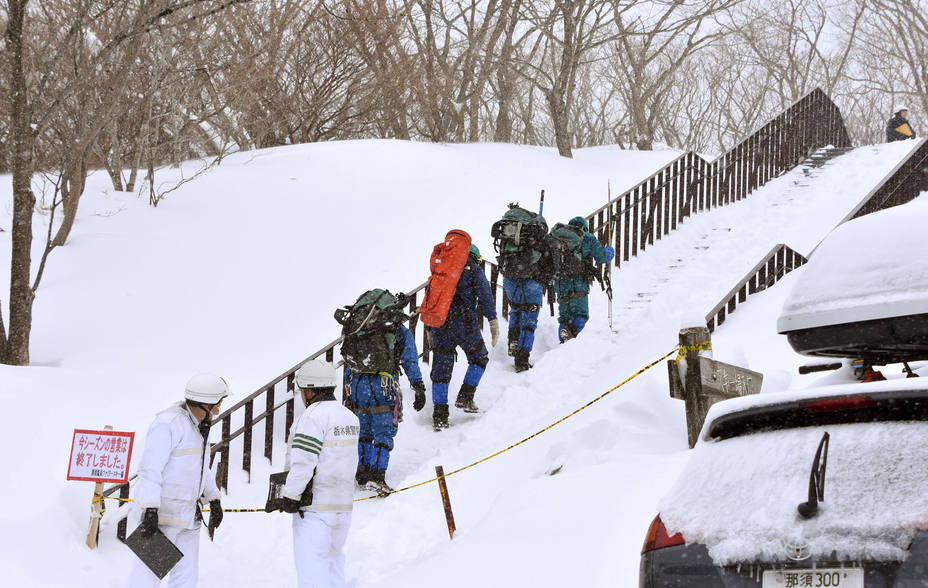 Rescue workers climb toward a mountain for searching missing people after an avalanche near a ski resort in Nasu town