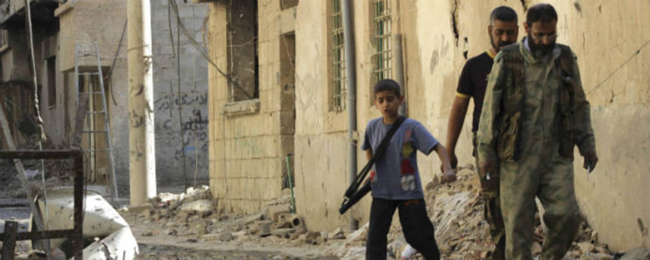 Un niño armado con una ametralladora acompaña a miembros del ejercito libre, oposición a Al Assad.REUTERS