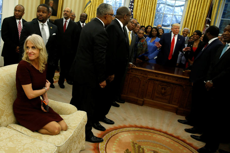 La Consejera de Trump, Kellyanne Conway, arrodillada en el sofá del despacho oval, mientras el presidente charla con con líderes de universidades negras.
