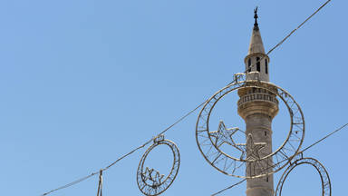 Ramadan decorations hanging in the street at Eid in front of a mosque minaret in Madaba in Jordan