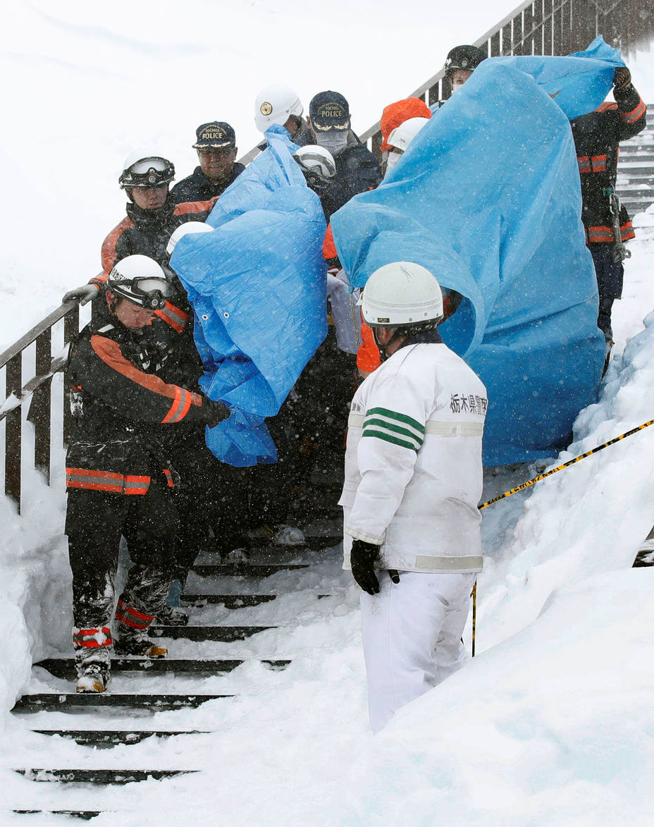 Rescue workers carry victims after an avalanche hit a group of high school students and teachers climbing near a ski resort in Nasu town
