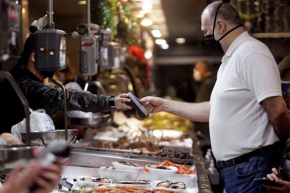 Un consumidor paga su compra de pescado y marisco este jueves en la plaza de Lugo, en la ciudad de A Coruña
