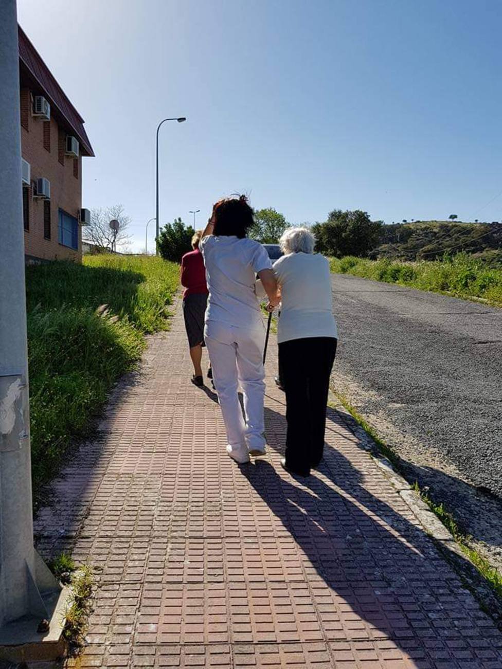Enfermos de Alzhéimer junto a su cuidadora paseando por el centro de Afads
