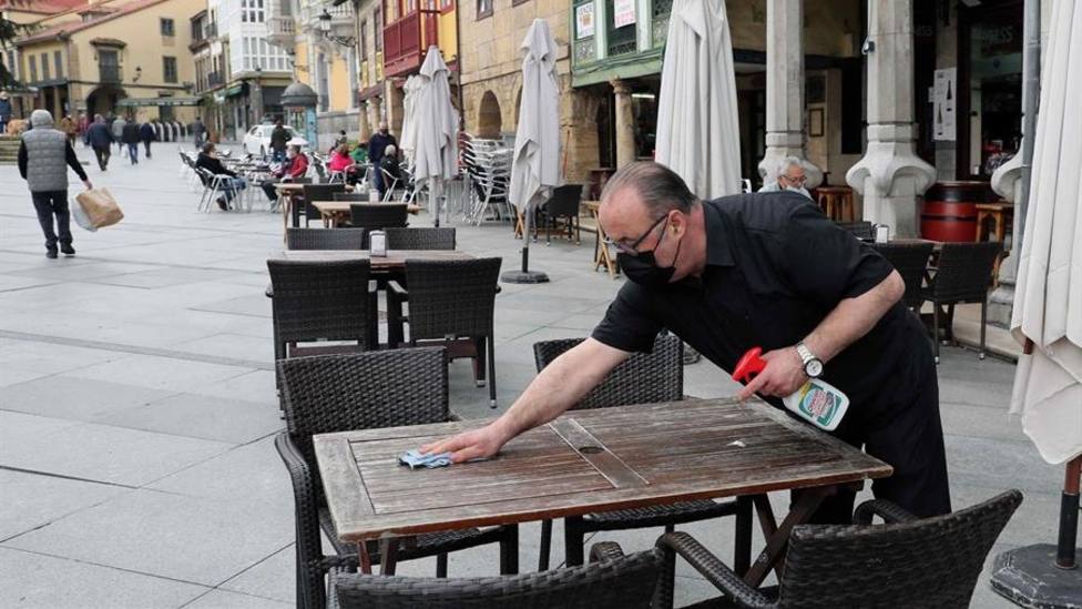 Un camarero desinfecta la mesa de una terraza del centro de Avilés