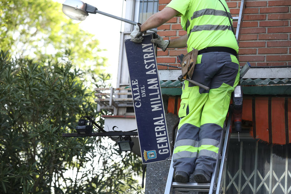 Un operario del Ayuntamiento de Madrid cambia la placa de la calle Millán Astray.