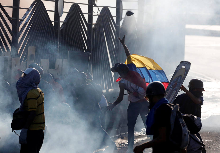 Opposition supporters throws stones into an air base while clashing with riot security forces during a rally against President Maduro in Caracas