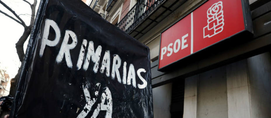 Un partidario de celebración de primarias, confecciona una pancarta a las puertas de la sede del PSOE en la calle Ferraz. EFE