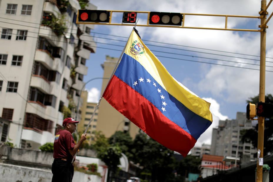A man with a Venezuelan flag stands in a street after a strike called to protest against Venezuelan President Nicolas Maduros government in Caracas