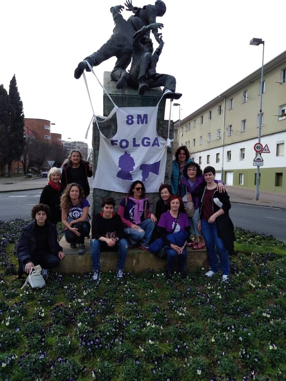 Integrantes de Galegas 8M Ferrolterra ante al estatua del 10 de Marzo, en Recimil