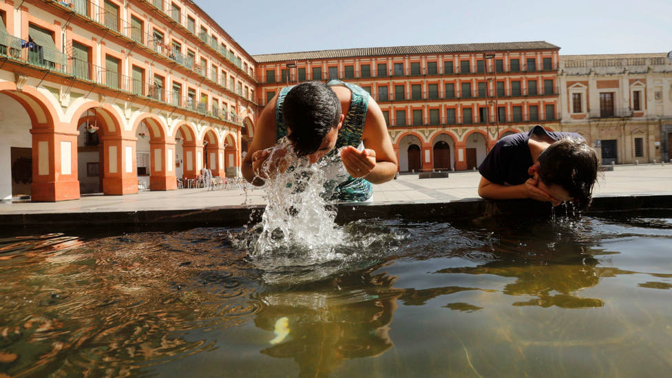 Unos niños se refrescan en una plaza de Córdoba