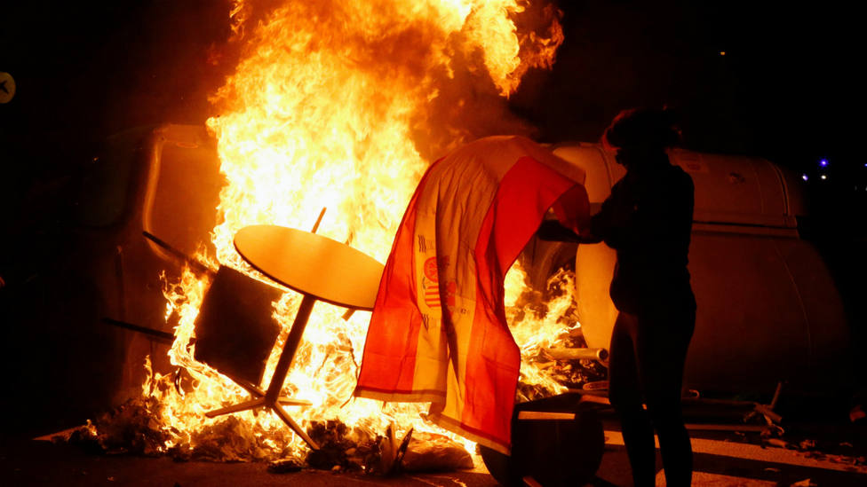 Un manifestante quema una bandera de España durante los altercados tras la concentración convocada por los CDR