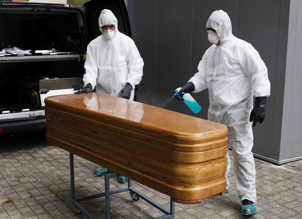 Operarios funerarios desinfectan un ataúd