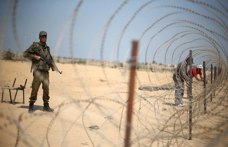 Un miembro de las fuerzas de seguridad palestinas, leales a Hamás, de guardia cuando los hombres establecen un alambre de púas en la frontera con Egipto