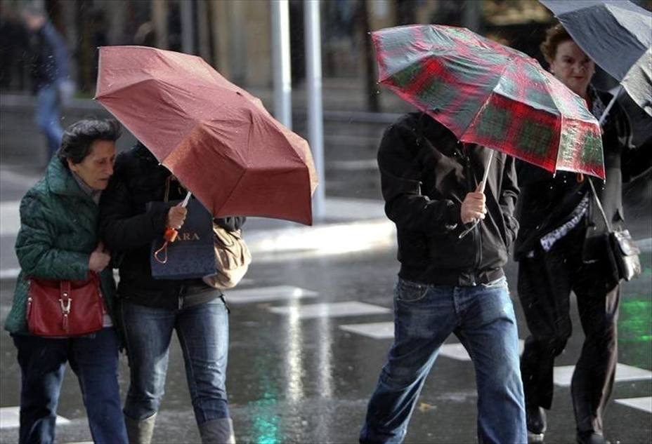 Llueve en la calle mientras unas personas se cubren con un paraguas