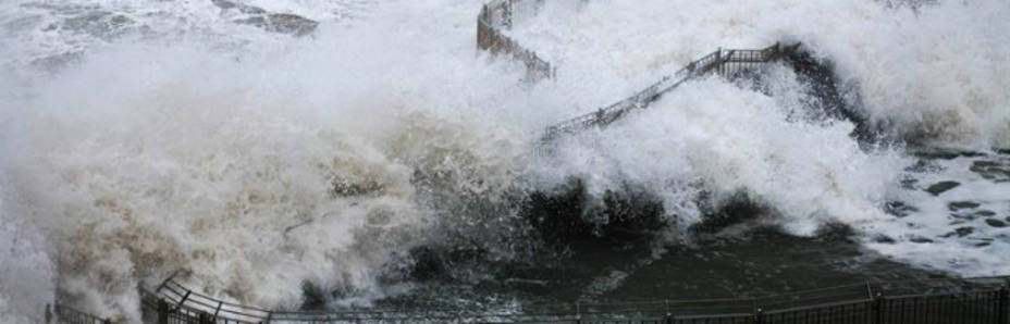 Una ola rompe en el faro de la isla de Mouro, frente a la Magdalena, Santander (EFE)
