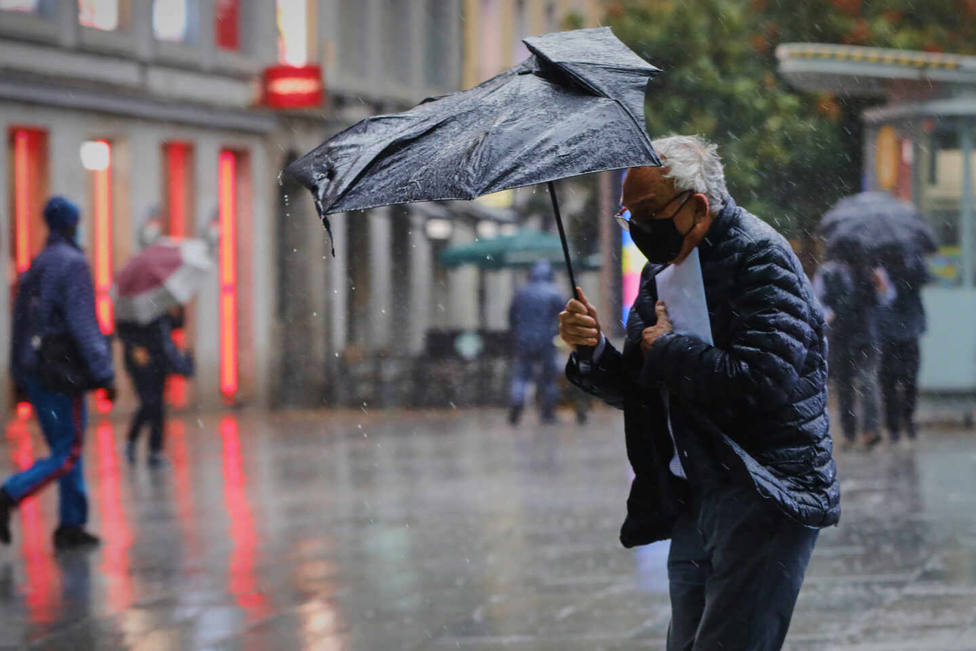 Hombre con paraguas afectado por el viento. Europa Press