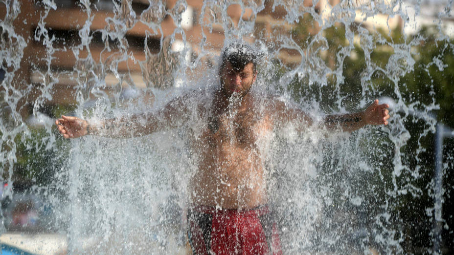 Un hombre se refresca en una fuente pública en Córdoba para combatir el calor