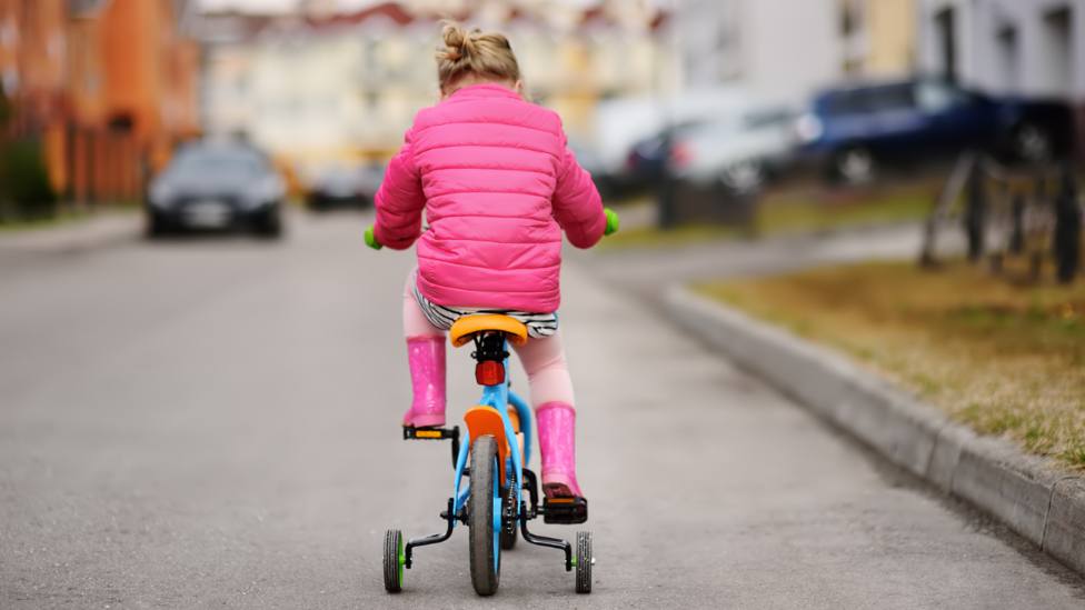 Foto de archivo de una niña disfrutando de su bicicleta en una zona urbana