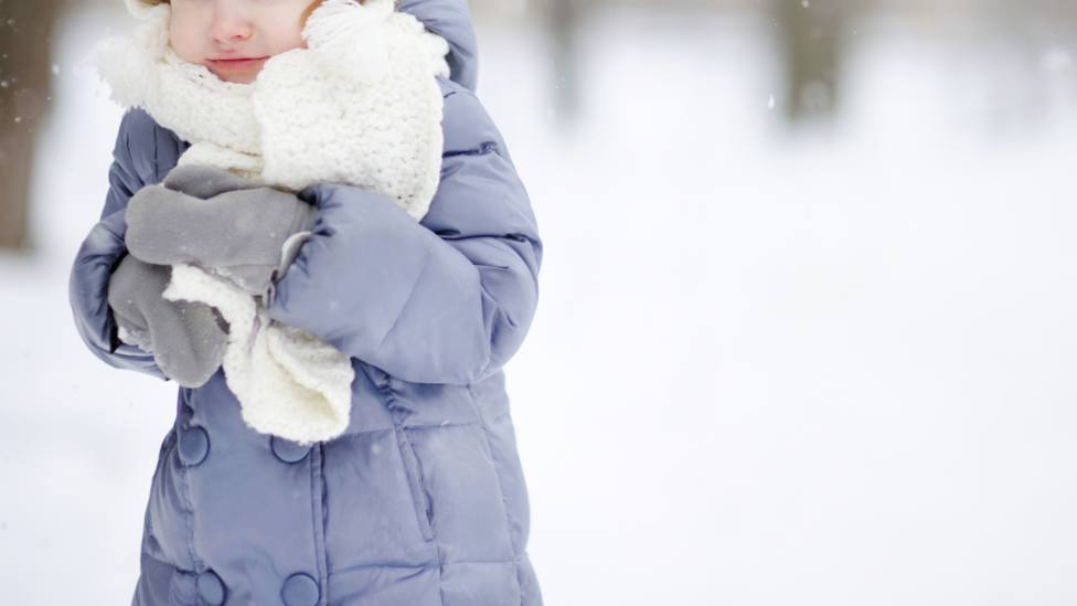Una niña con abrigo en la nieve