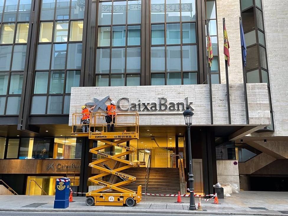 Operarios colocan el logo de CaixaBank en el edificio que albergaba la sede de Bankia en Valencia