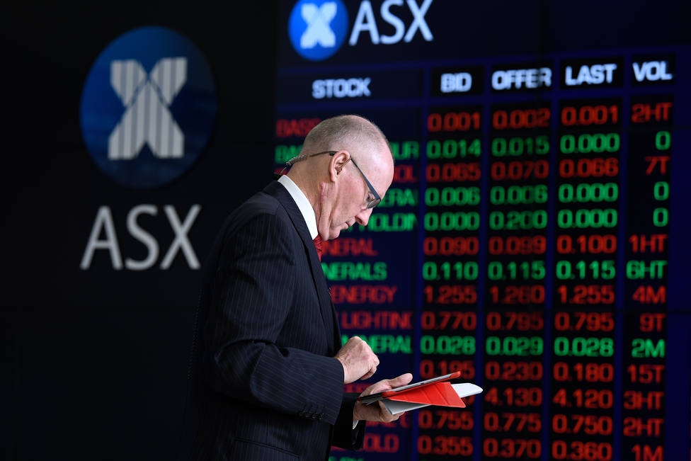 A journalist checks his iPad in front of the digital market boards at the Australian Stock Exchange (ASX) in Sydney, Friday, March 13, 2020. The ASX has fallen nearly seven per cent on opening after Wall Street suffered its biggest drop since the Bla