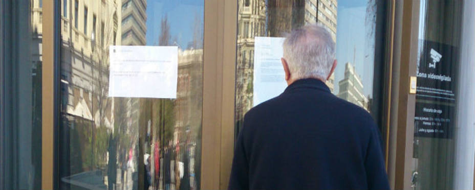Un cliente lee dos carteles a las puertas del Banco Madrid. Foto Belén Miguel