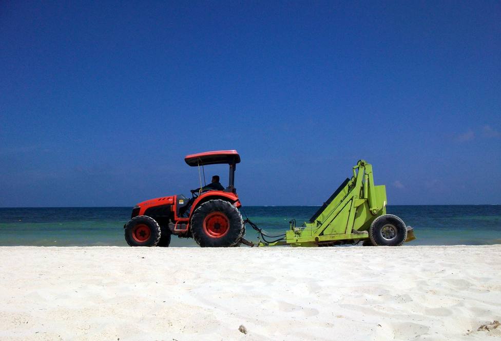 Foto de archivo de un operario limpiando una playa
