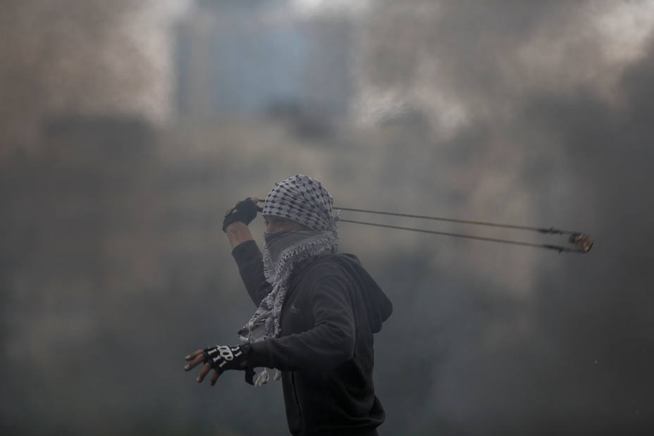 A Palestinian demonstrator hurls stones at Israeli troops during clashes at a protest marking Land Day, near Ramallah, in the occupied West Bank