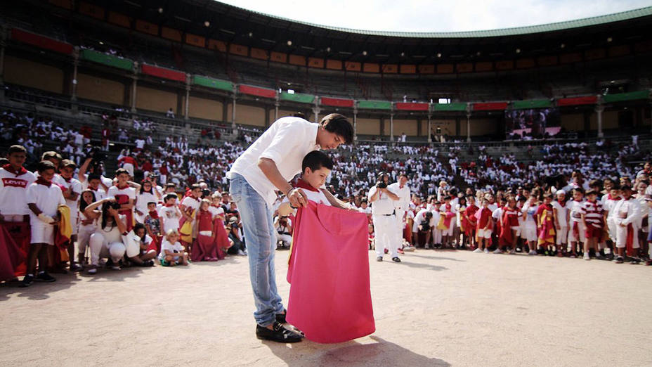 Andrés Roca Rey enseñando a coger una muleta a un joven aficionado pamplonés