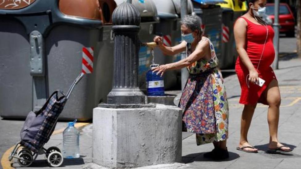 Una mujer llena una garrafa de agua en una fuente del barrio de La Torrassa de LHospitalet - ABC