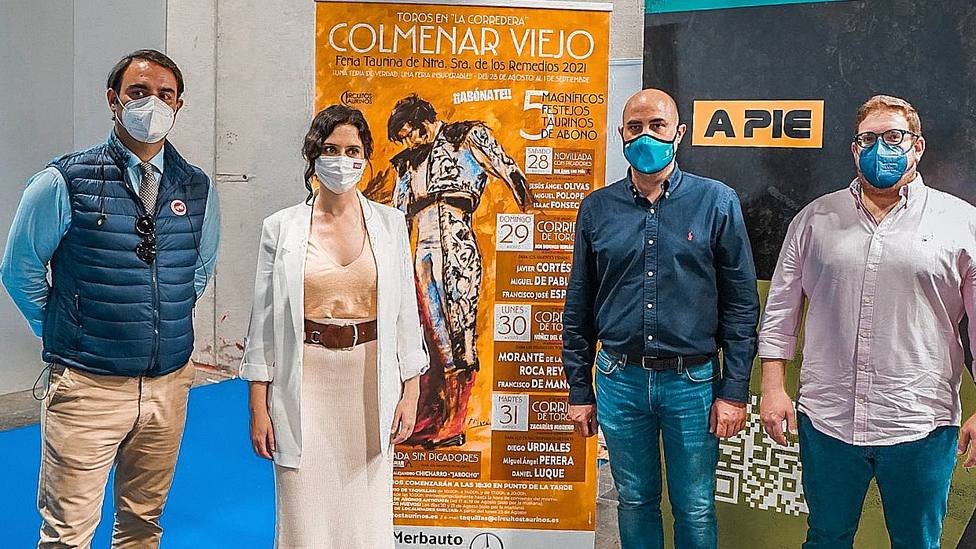 Isabel Díaz Ayuso junto a los carteles de la Feria de Colmenar Viejo presentados en FITUR