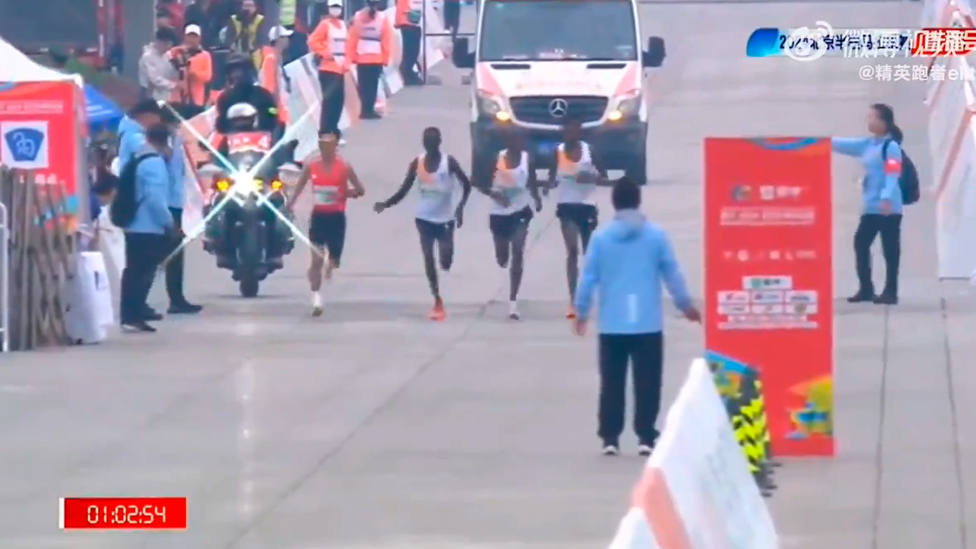 Momento en que un atleta le indica al local He Jie que les adelante en el medio maratón de Pekín