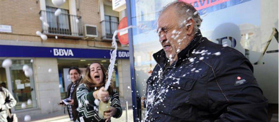 José Ramón Núñez (d), responsable de la administración de loterías situada en la calle Constitución de Mora (Toledo), celebra que ha vendido una serie del segundo premio del Sorteo de Navidad, el 12.775, con lo que ha repartido un total de 1.250.000