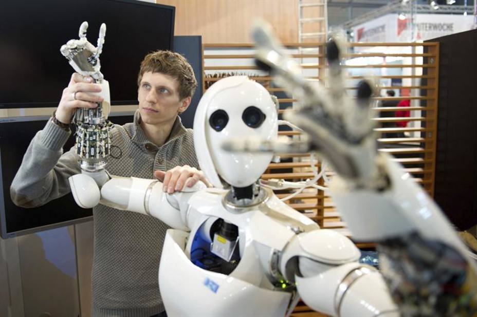 El investigador del Centro de Investigación Alemán sobre Inteligencia Artificial,Dennis Mronga, ajustando un brazo del Robot AILA, en un mostrador de la feria.