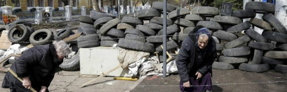 Manifestantes prorrusos limpian el suelo junto a una barricada frente a una estación de policía ocupada en Kramatorsk (EFE)