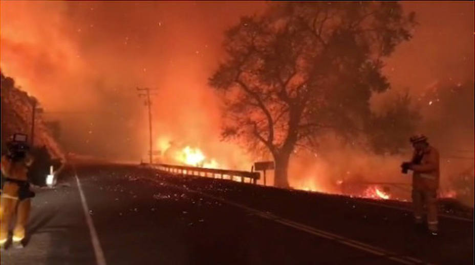A man takes pictures of wildfires from a highway