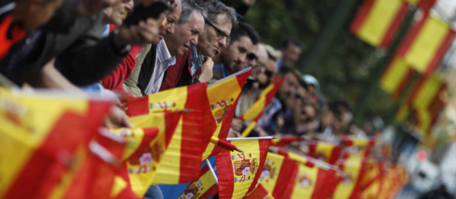 Asistentes al acto central del Día de las Fuerzas Armadas, portan banderas de España en las inmediaciones de la Plaza de la Lealtad de Madrid. Foto: EFE