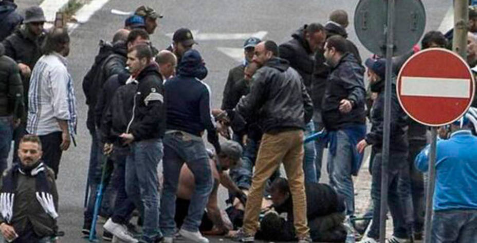 Aficionados del Nápoles rodean a uno de los hinchas heridos.