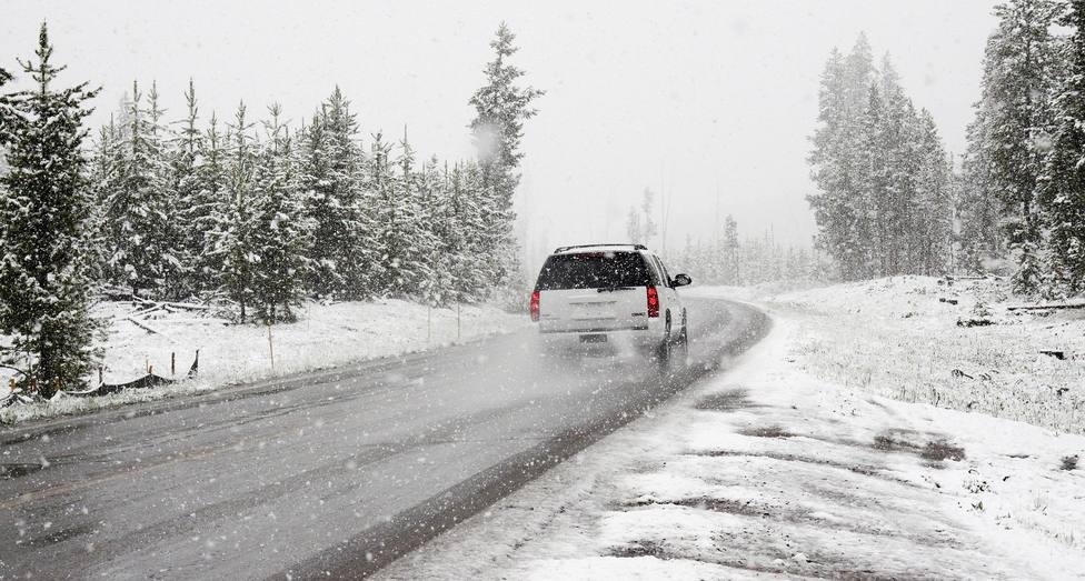 Un coche circula por una carretera nevada