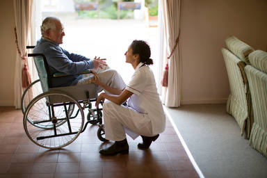 Enfermera hablando con paciente en silla de ruedas
