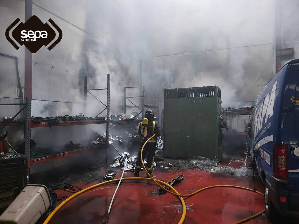 Bomberos sofocando el fuego en el interior de una nave en Parres