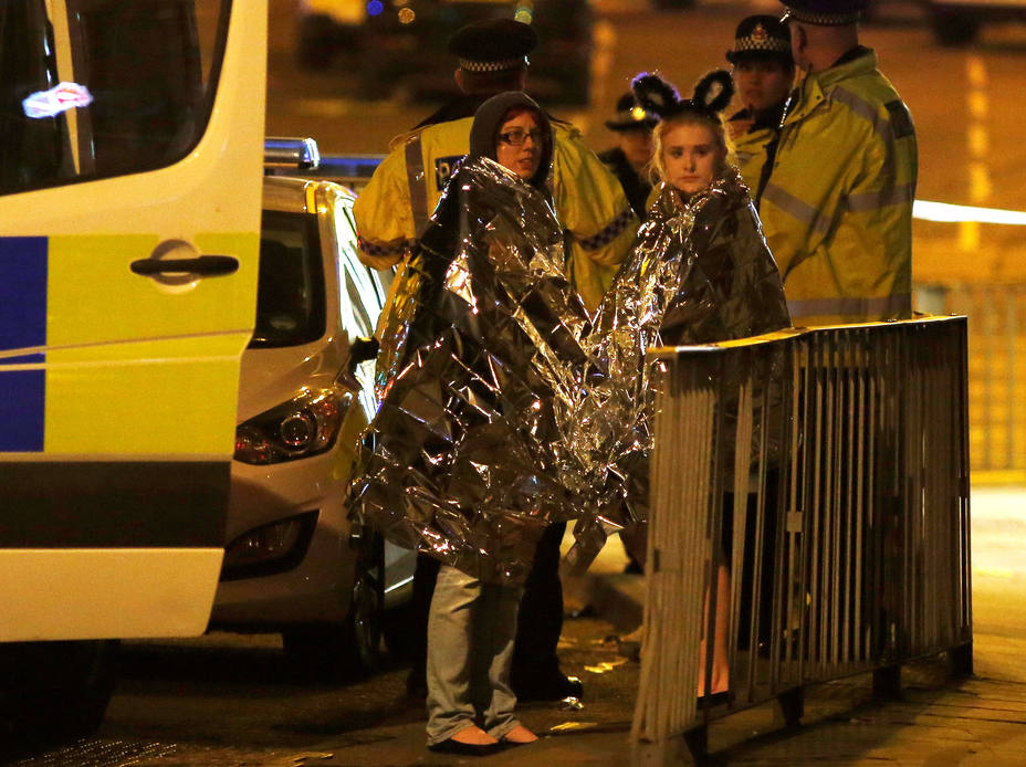 Two women wrapped in thermal blankets stand near the Manchester Arena, where U.S. singer Ariana Grande had been performing, in Manchester, northern England, Britain