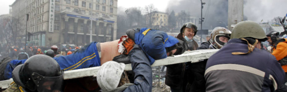 Varios hombres trasladan a un herido en la plaza de la Independencia de Kiev (Reuters)