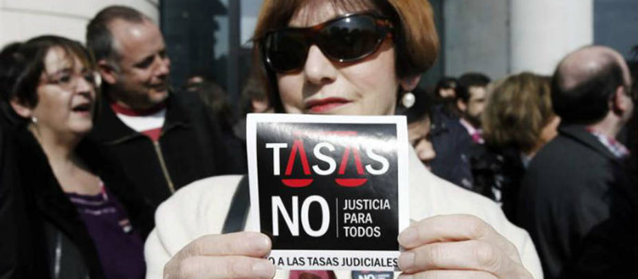 Una mujer muestra una pegatina contra las tasas judiciales. EFE