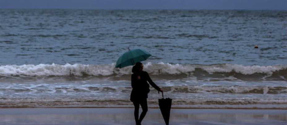 Una mujer posa en una solitaria playa de La Concha de San Sebastián mientras llueve. EFE